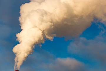 smoke from a pipe in the factory against a blue sky