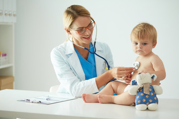Female doctor is listening kid with a stethoscope in clinic