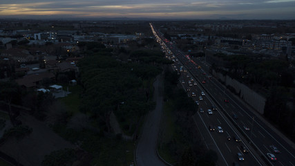 Aerial sunset view of an industrial area of a large Italian city with warehouses, warehouses, offices and buildings. Among the asphalt roads beyond the cars, vans and trucks there are trees.