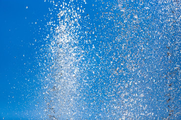 Splashing water from a fountain against the blue sky