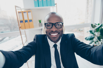 Close up self portrait of stylish, cheerful, attractive man shooting selfie in two hands, smiling at camera, standing in work place, station, having fun, timeout