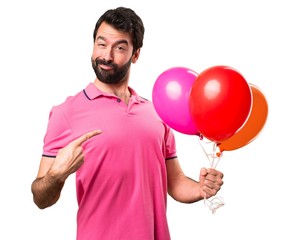 Handsome young man holding balloons over isolated white background