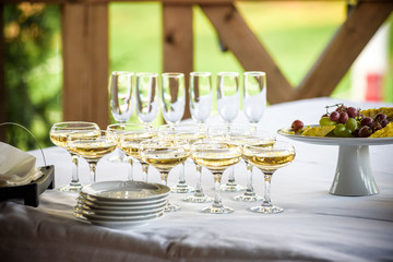 Glasses, forks, knives, napkins and decorative flower on a table served for dinner in cozy restaurant.