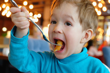 child eats nuggets with a fork in a cafe