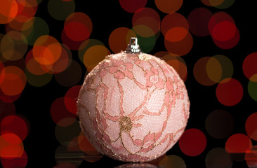 Beautiful Christmas pink ball toy, embellished with lace, on dark background