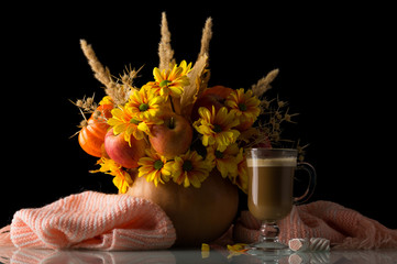 Original autumn composition in pumpkin, nearby Cup of cappuccino and warm scarf isolated on black
