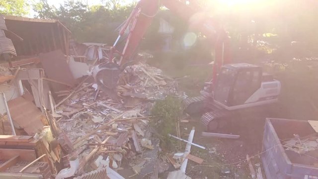 Rising High Past Excavator Bucket Filling Dumpster at Sunrise