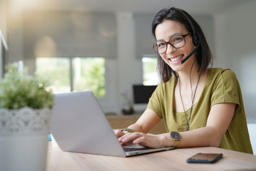 Teleoperator working in office with laptop and headset on