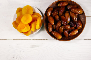 Dried apricots and dates fruit on white wooden table. Top view