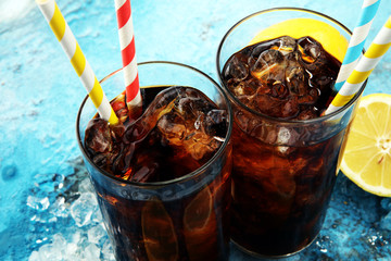 Softdrink with ice cubes, lemon and straw in glass.