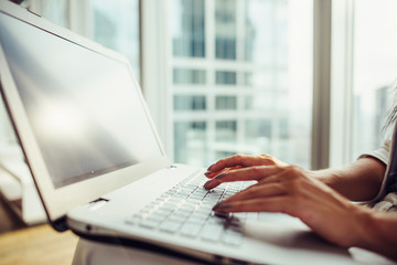 Woman using laptop sitting in modern office close up