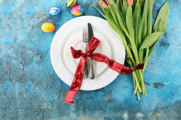 Festive table setting for Easter with fork, knife and tulip.