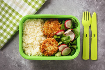 Lunch box with boiled rice, chicken cutlets ans radush salad.