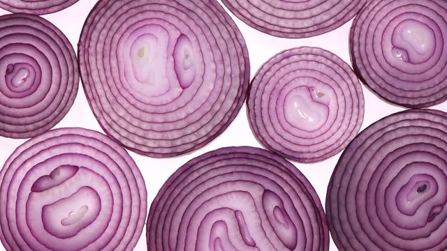 Sliced red onion rings rotating on white in 4K. Closeup top view of healthy food background with vegetable of rich vitamin.
