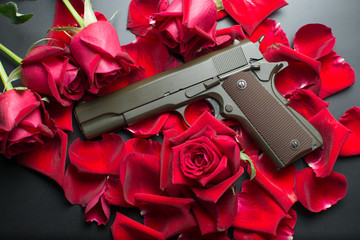 Gun and red roses flower on dark background