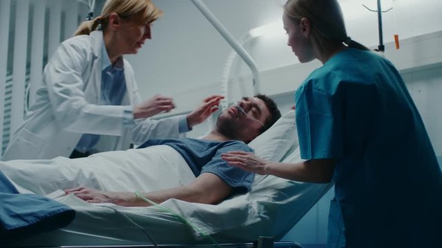 Emergency in the Hospital, Doctor and Nurse Rush into the Ward to Safe Dying Patient. Man is Lying on the Bed without Signs of Life. Doctors Do Everything to Resuscitate Him. 