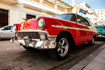 Fotobehang Cuba, Havana: American classic car with cuba flag parked on the street  © Lena Wurm