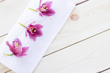 Spa and wellness setting with orchid, towel on wooden white background closeup