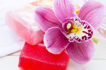 Fototapeta na wymiar Spa and wellness setting with orchid and red soap on wooden white background closeup