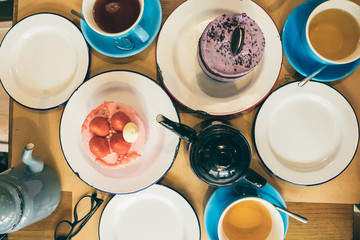 a dining table with sweets and a cup and a kettle with tea. top view from above