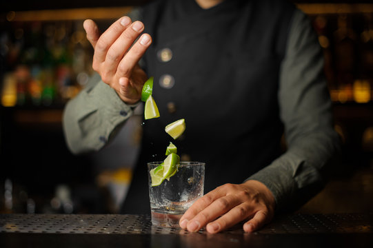 Barman adding slices of lime into the glass