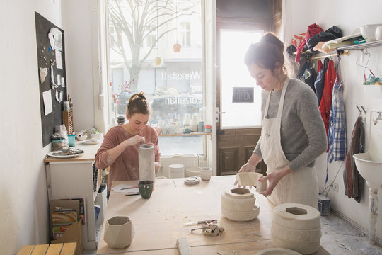 Two ceremic artists are working on their ceramics in a pottery workshop.