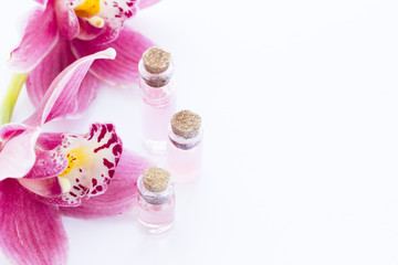 Spa and wellness setting with orchid and red oil in a bottle on wooden white background closeup