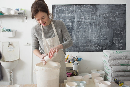 A ceremic artist is glazing ceramics in a pottery workshop.