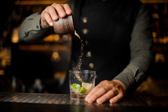 Bartender pouring cane sugar into the cocktail glass