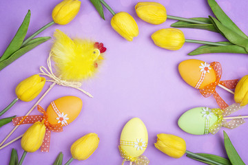 Fototapeta na wymiar Easter frame with decorative eggs and tulip on purple background. Space for text.