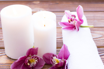 Spa and wellness setting with orchid, towel and candle on wooden dark background closeup