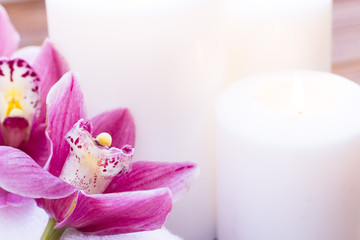 Spa and wellness setting with orchid, towel and candle on wooden dark background closeup