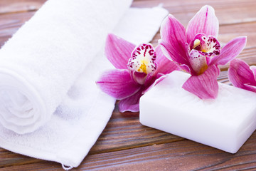Fototapeta na wymiar Spa and wellness setting with orchid, towel and soap on wooden dark background closeup