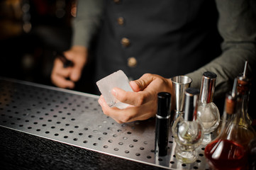 Barman hand holding a large rectangular piece of ice