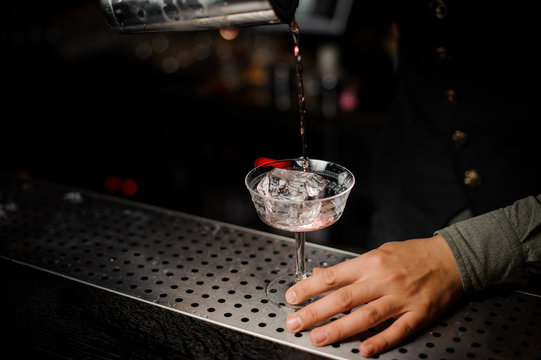 Barman pouring a cocktail with campari into a glass