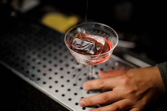 Male hand holding an elegant cocktail glass with sweet alcoholic drink