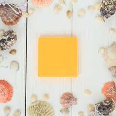 orange sheet of paper and seashells on a wooden background.Travel background