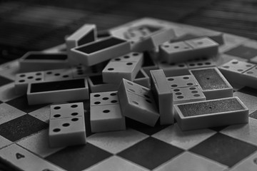 Monochrome Chaotic pile of domino pieces on the bamboo brown wooden table background.