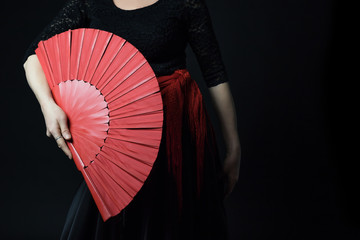 Low Key photo of Flamenco Dancer middle age woman posing with her red fan. All on the dark...