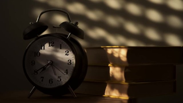Alarm clock and old books on the shelf in the morning, concept of education and reading
