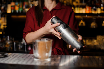 Female bartender shaking a drink behind the bar counter