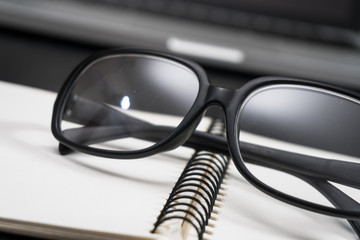 Black framed glasses on the computer keyboard with a very shallow depth of field. Copy space for text