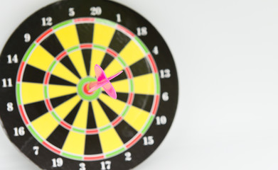 Close up pink darts arrow on the target center of dartboard with white background for business goal concept