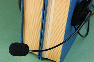 Headphones with a microphone and a stack of books on a green background