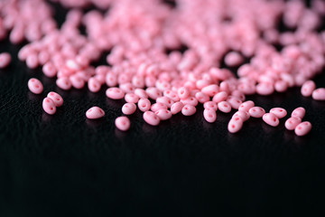 Scattered twin beads pink color on a dark surface close up