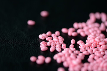 Scattered twin beads pink color on a dark surface close up