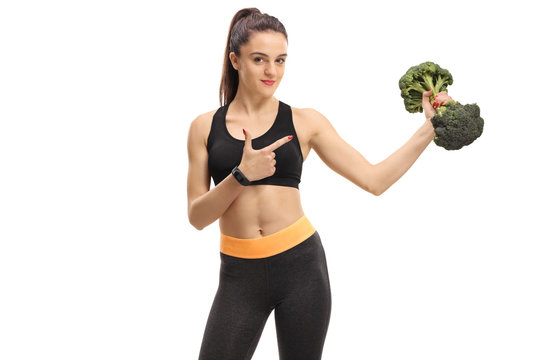Fitness woman lifting a broccoli dumbbell and pointing