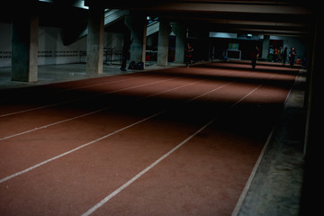 Athletics people running on red running track at night