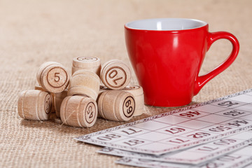 Board game lotto on sackcloth. Wooden lotto barrels and game cards with cup of coffee