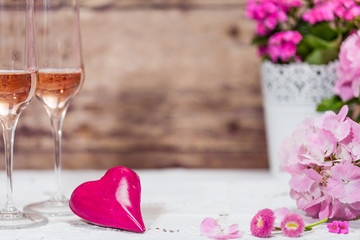Rosa Blumendeko mit rosa Herz und zwei Gläsern rosa Champagner